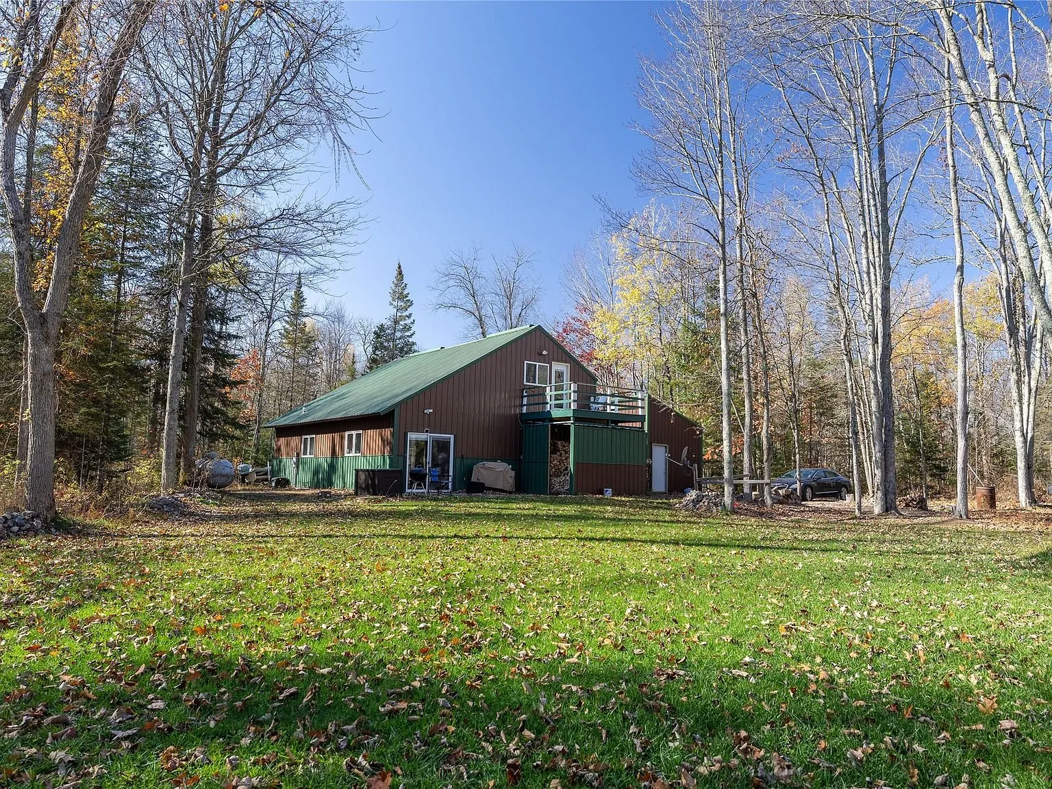 The home seen from across the open mowed yard in fall color