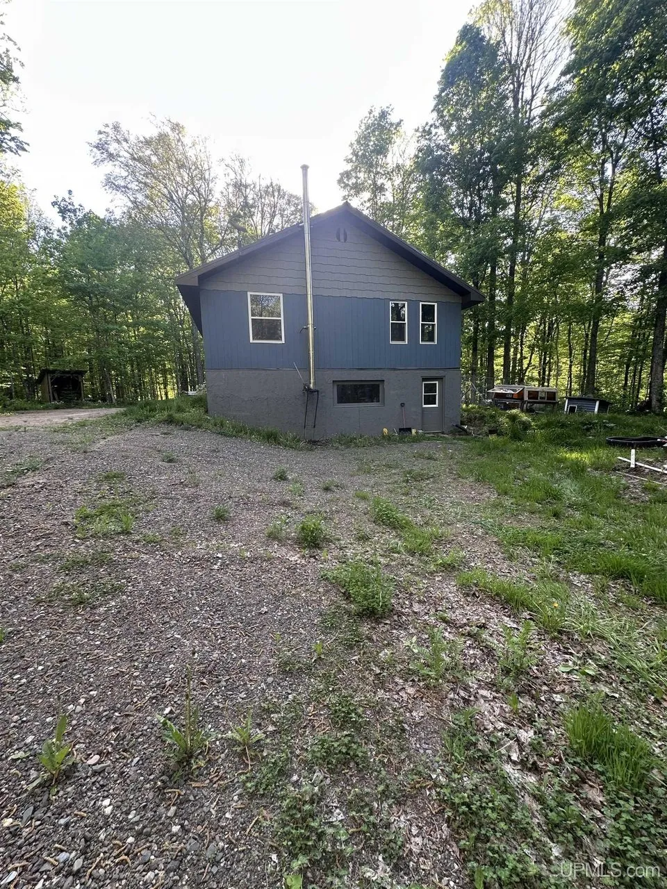 The gable end of the cabin above the gravel slope