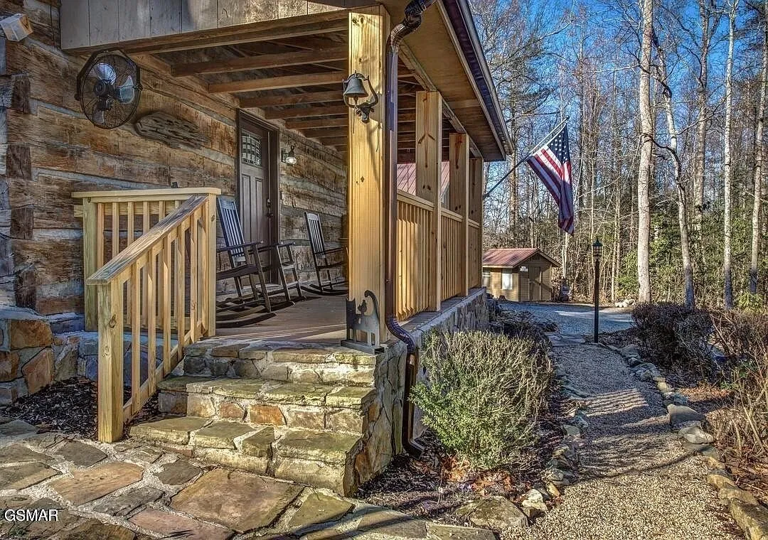 The side of the cabin with stone steps and a railed entry landing