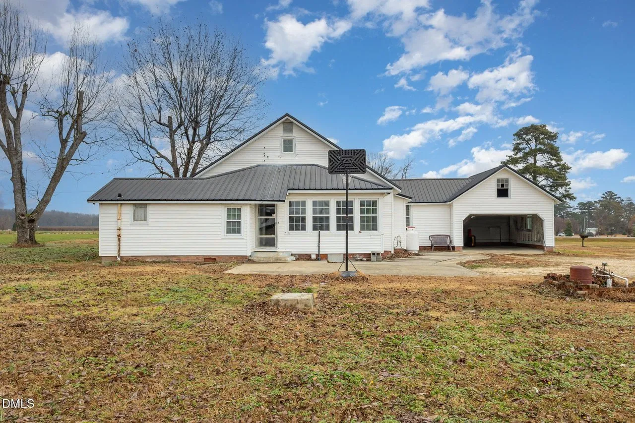 The rear of the house with the sunroom's wall of windows and the carport at the right