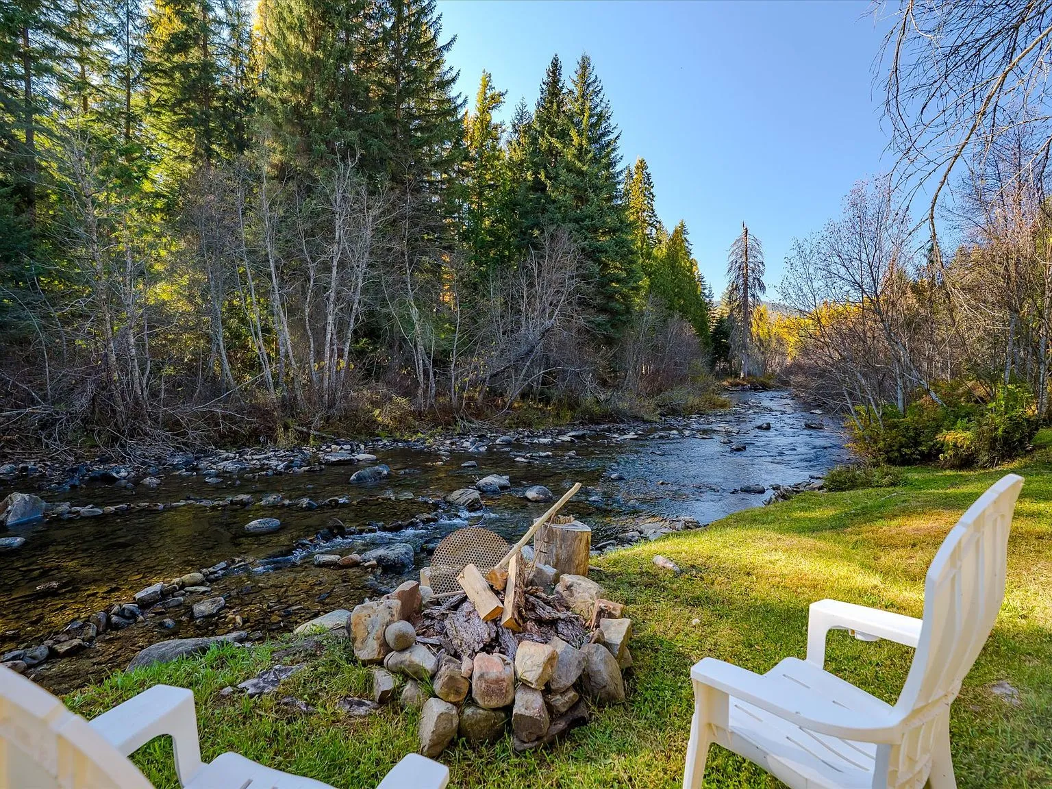 The creek running through the property, lined by rocks and tall pines in afternoon light
