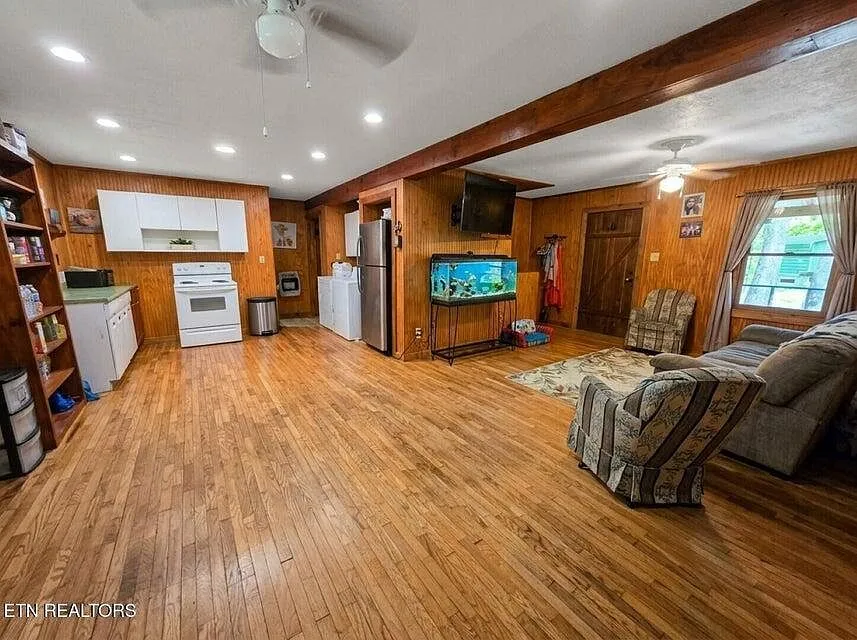 The kitchen with white cabinets, a range and an open living area beyond