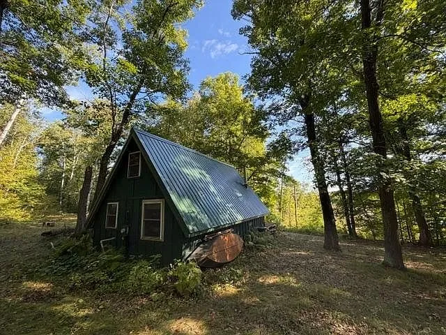 The A-frame from the woods with the pond through the trees behind