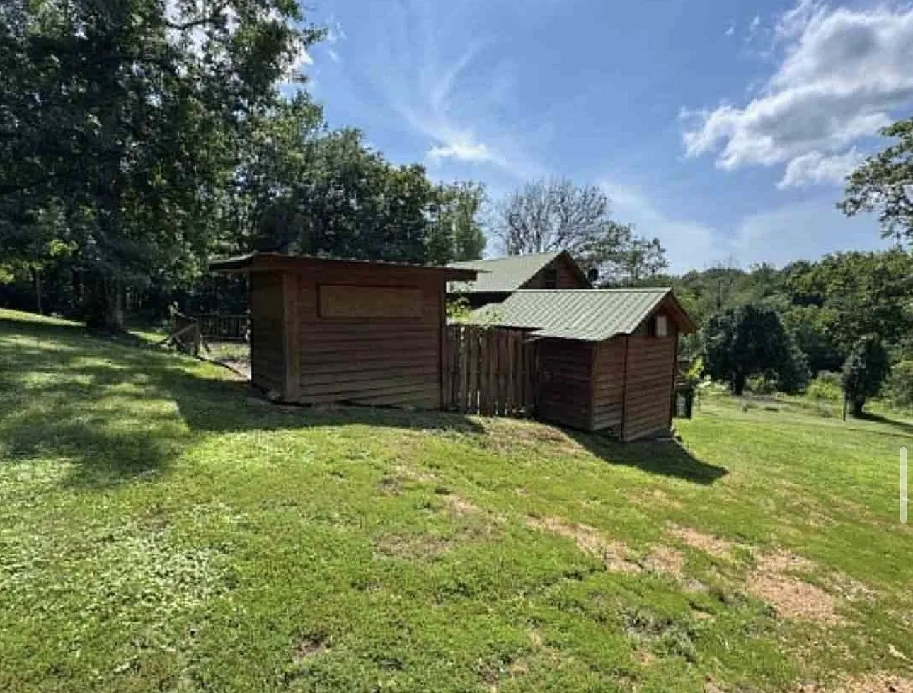 The outbuilding standing apart from the cabin at the edge of the clearing