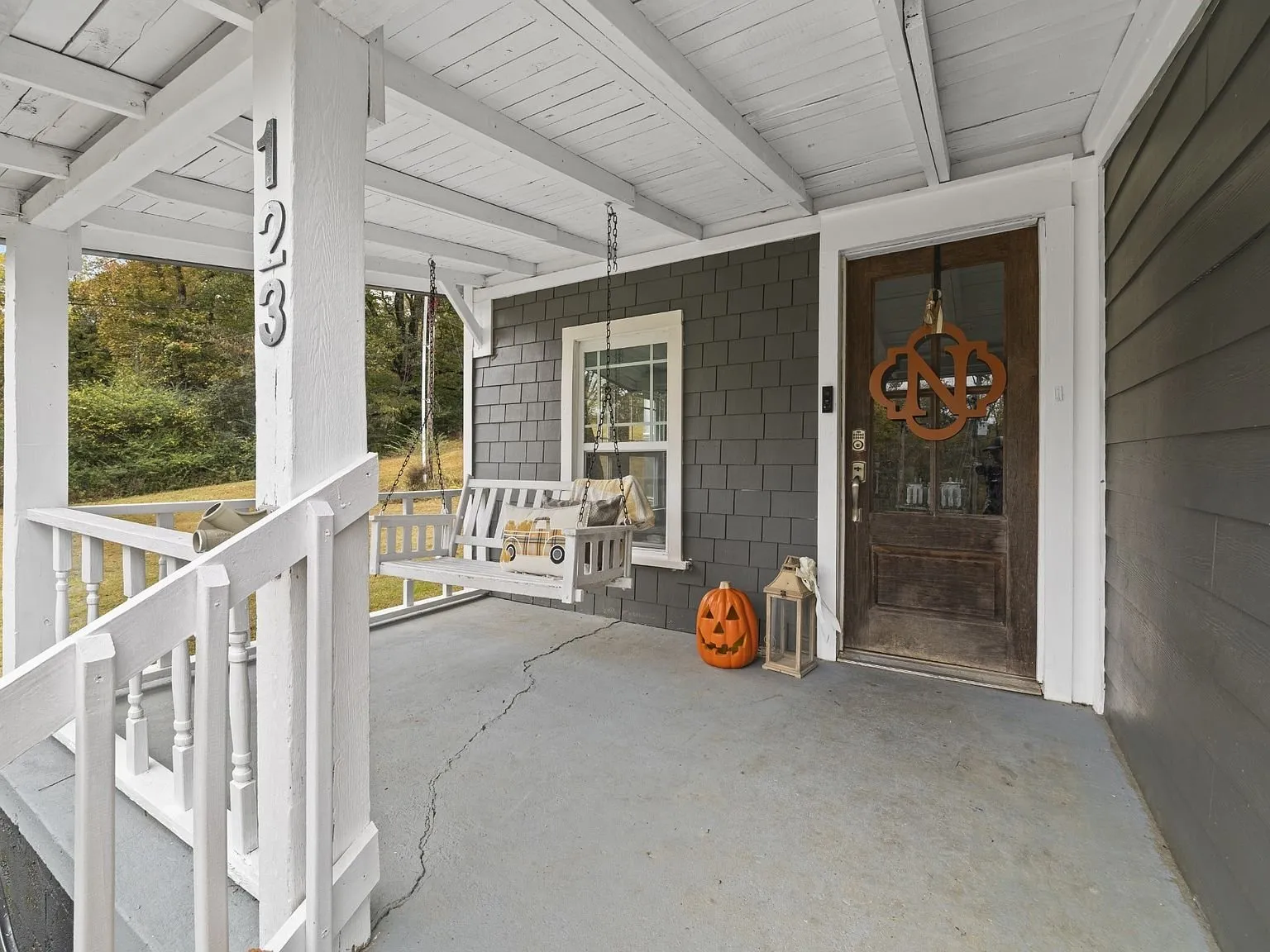 The covered front porch with a swing and the front door