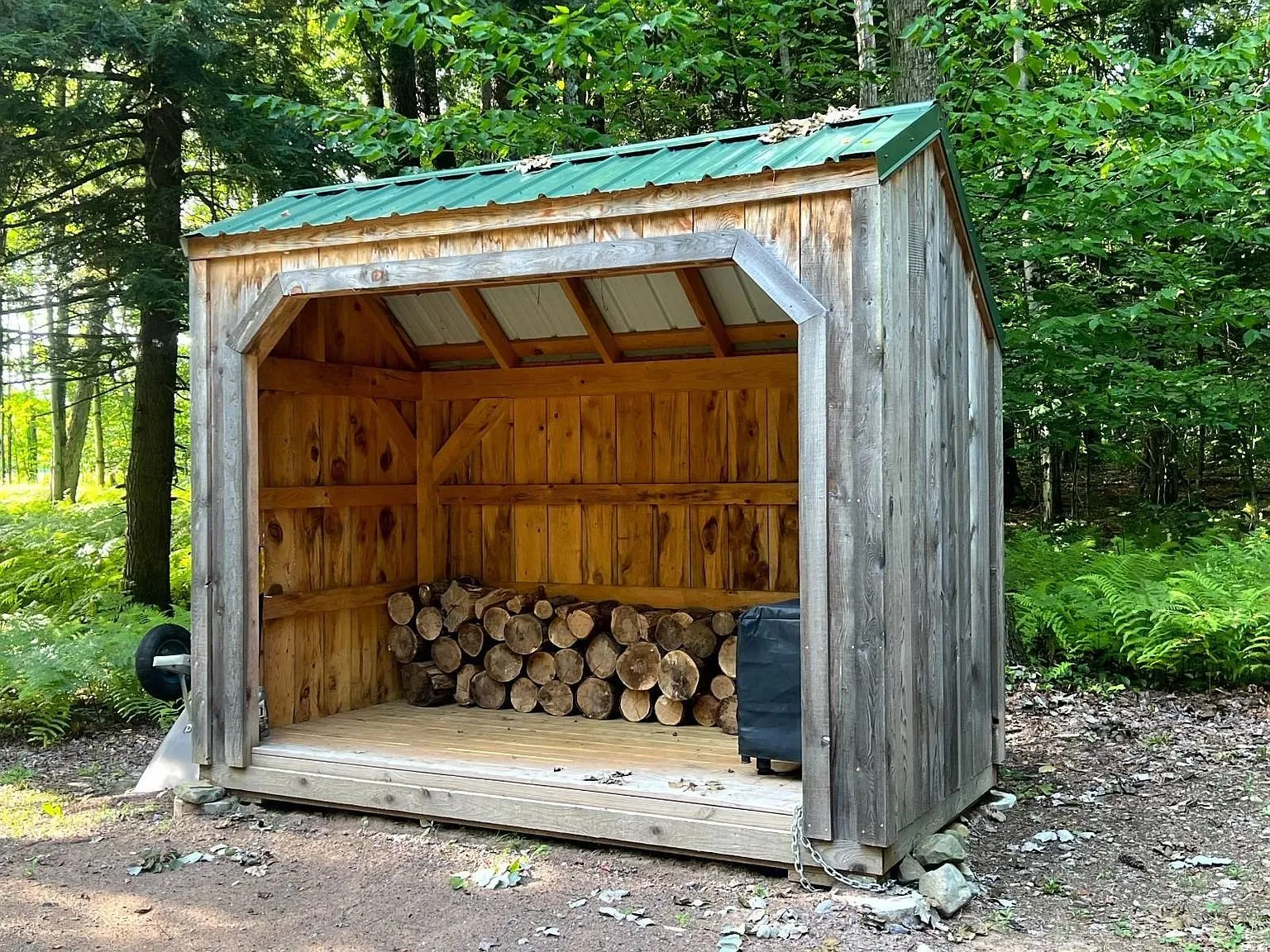 The open woodshed with a stack of split firewood