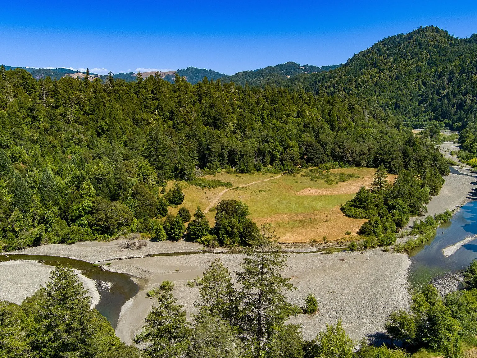 An aerial view of the river corridor winding below the property through gravel bars and trees