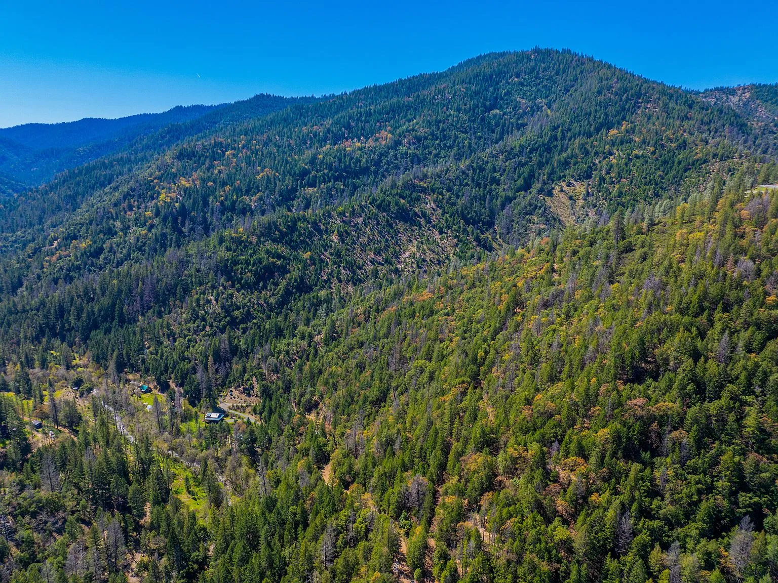 A wide aerial view of forested mountains surrounding the property