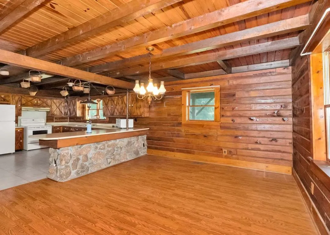 An upstairs bedroom with a second stone fireplace and sloped wood ceiling