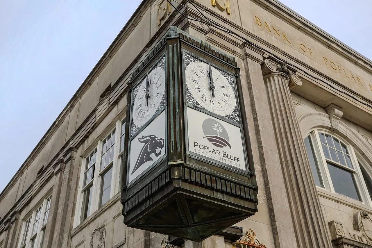 The corner clock on its bracket against the limestone facade