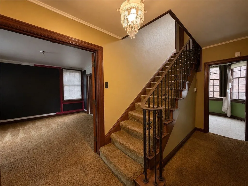 The entry hall with the carpeted stair and iron balusters