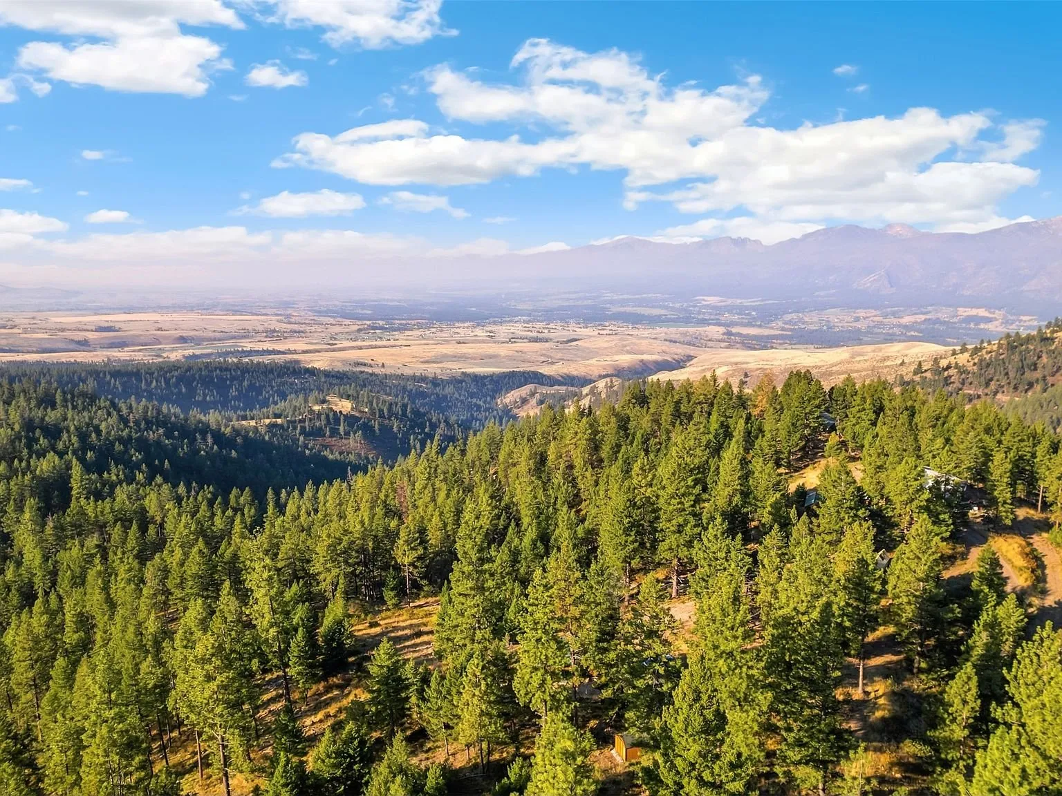 A wide aerial view of forested ridgelines and the valley beyond