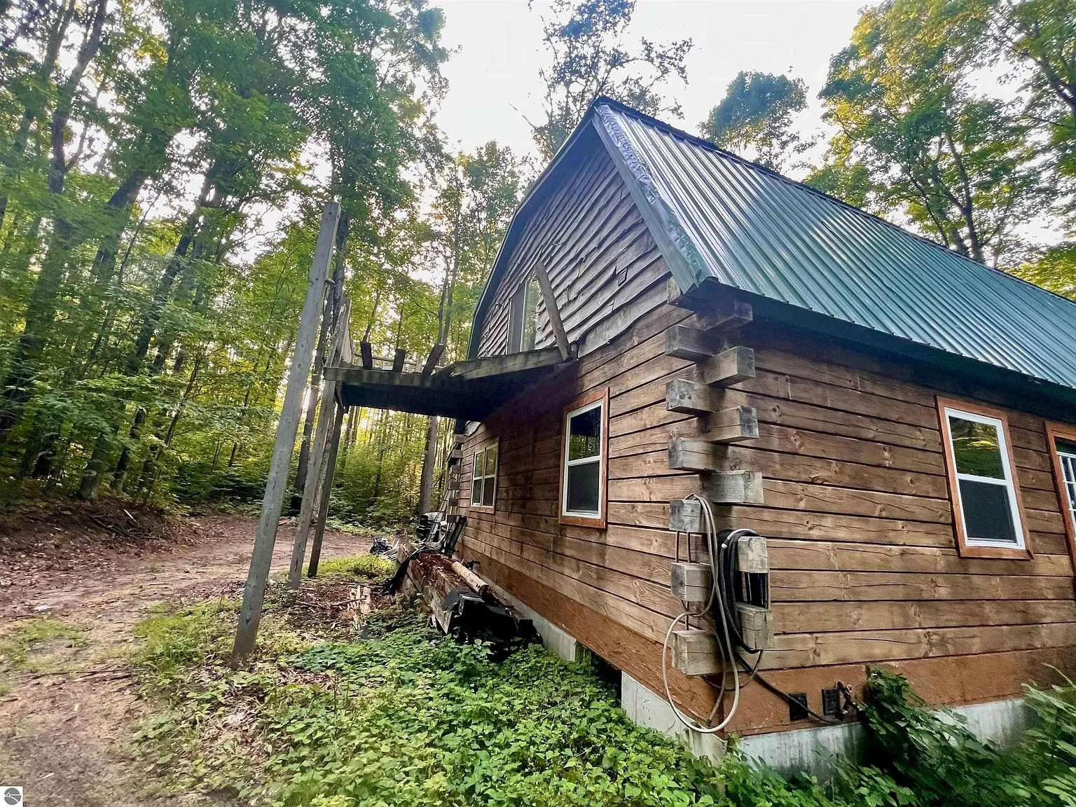 The side of the cabin with the square logs, the shakes in the gable and the balcony