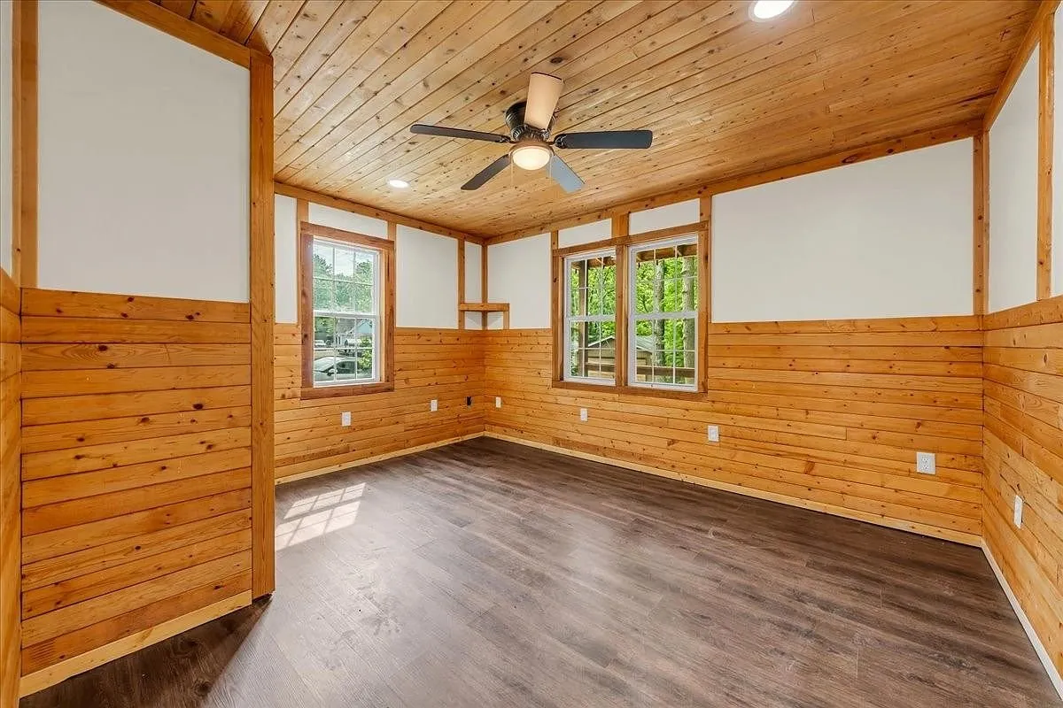 A second pine-walled room with a window and overhead storage panel