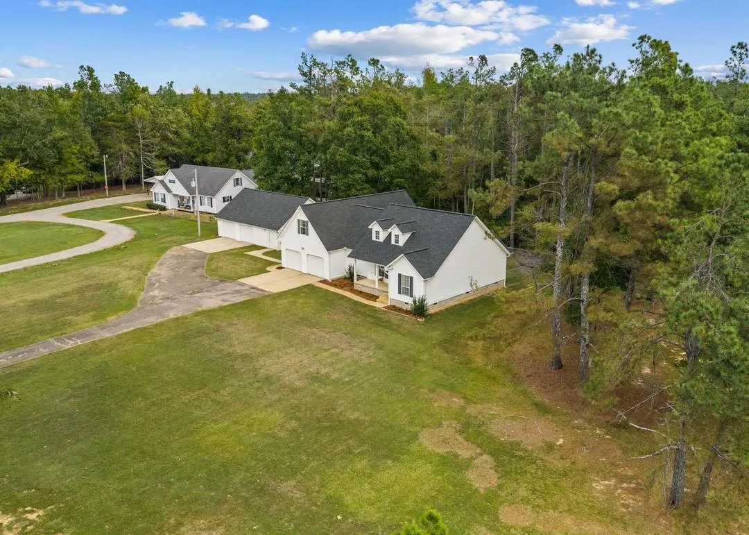 A second aerial view showing the full clearing and the driveway's path through the trees