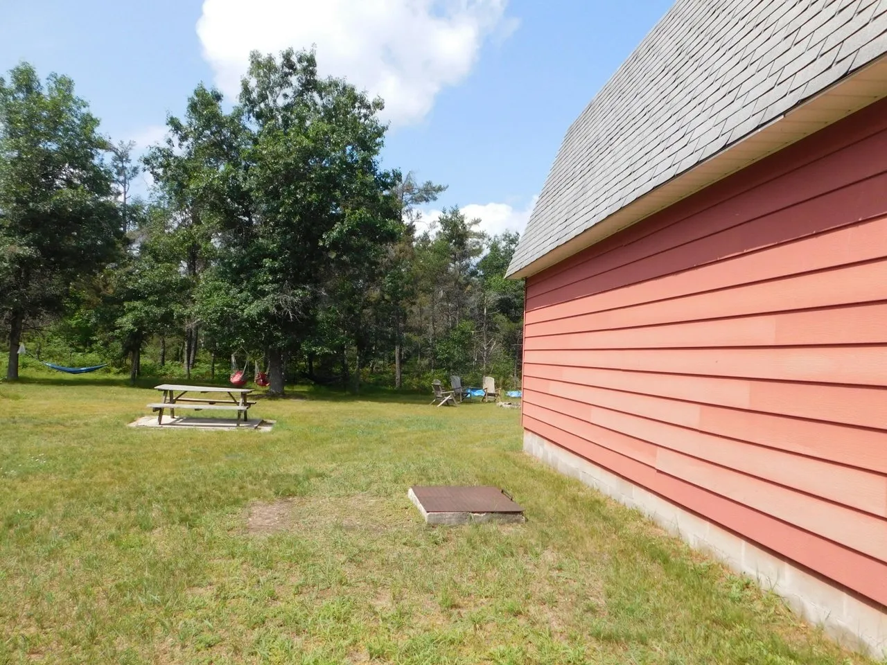 The red garage wall and the side yard running back toward the trees