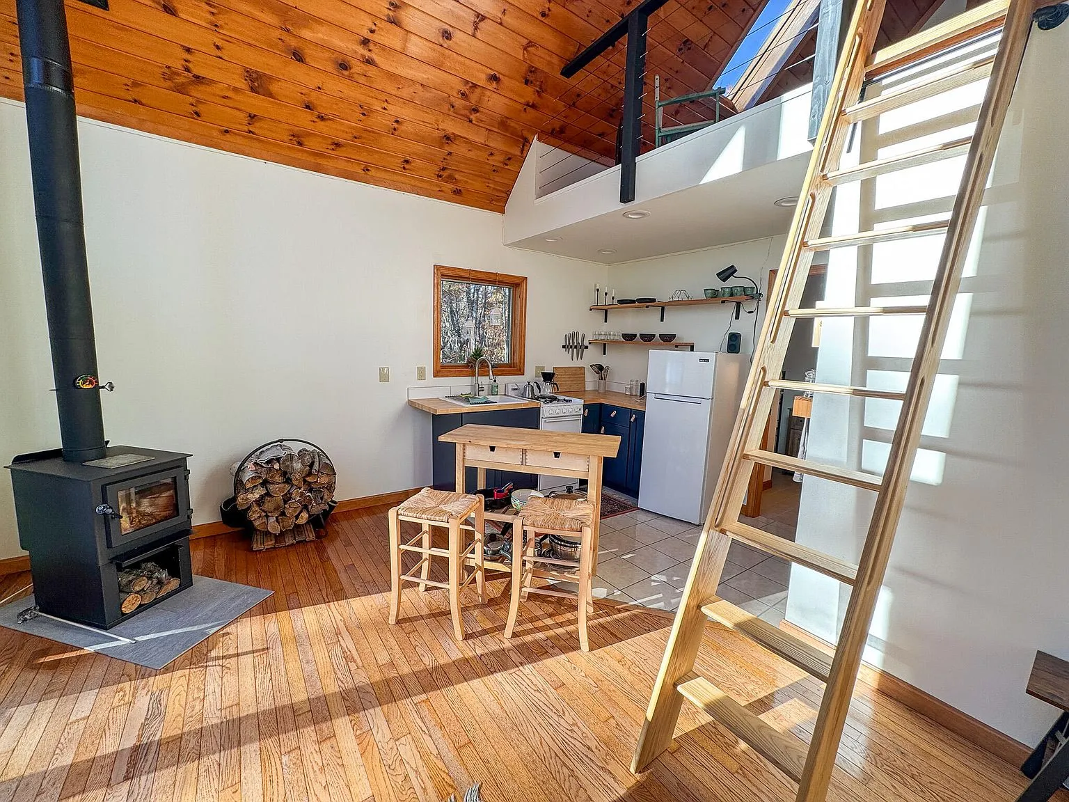 A wide interior view of the chalet's great room, floor-to-ceiling windows and wood stove