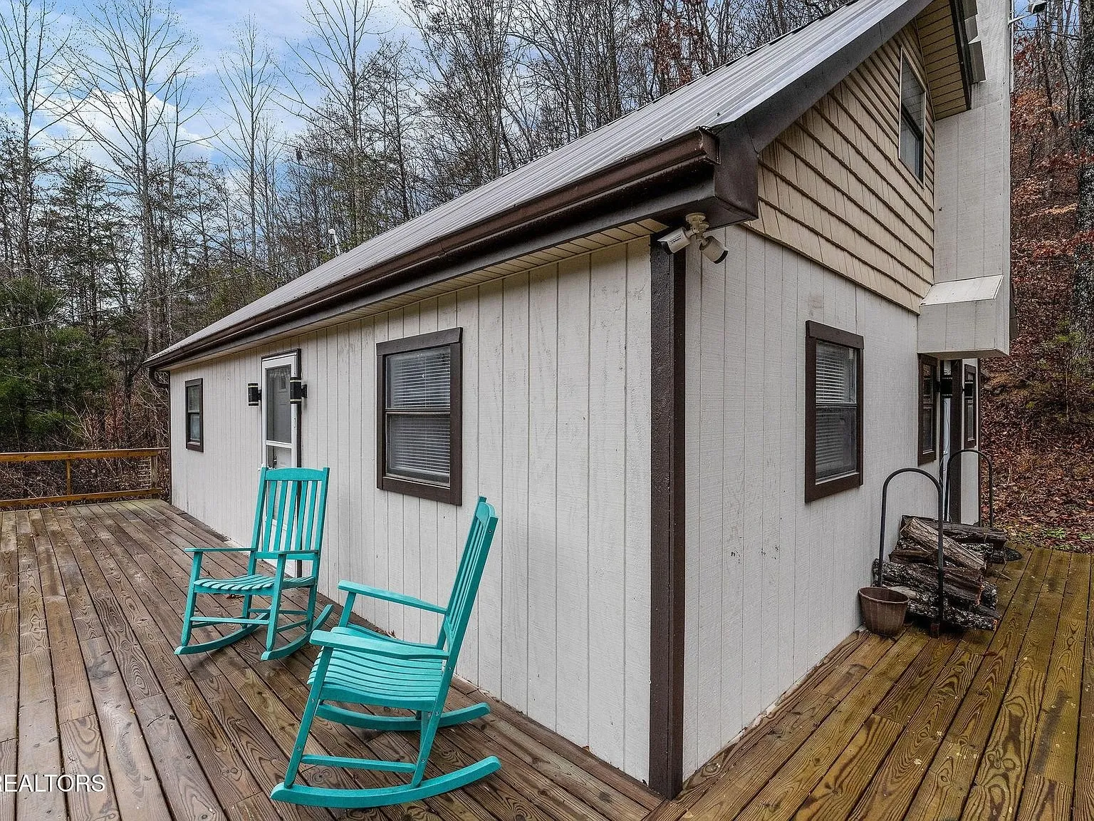 The side deck with two teal rocking chairs and a firewood rack