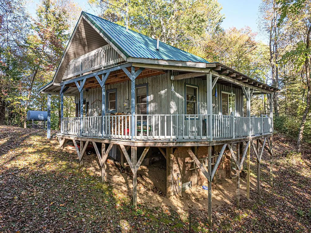 The cabin's second-level balcony and wraparound porch from the side yard