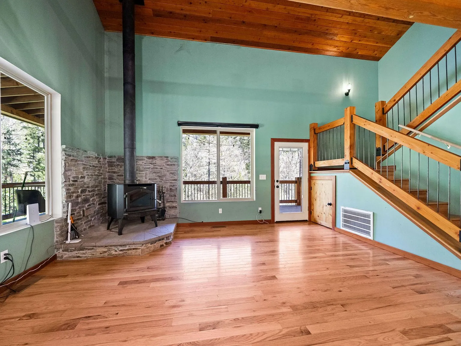 The living room with a wood stove, sage walls and hardwood flooring