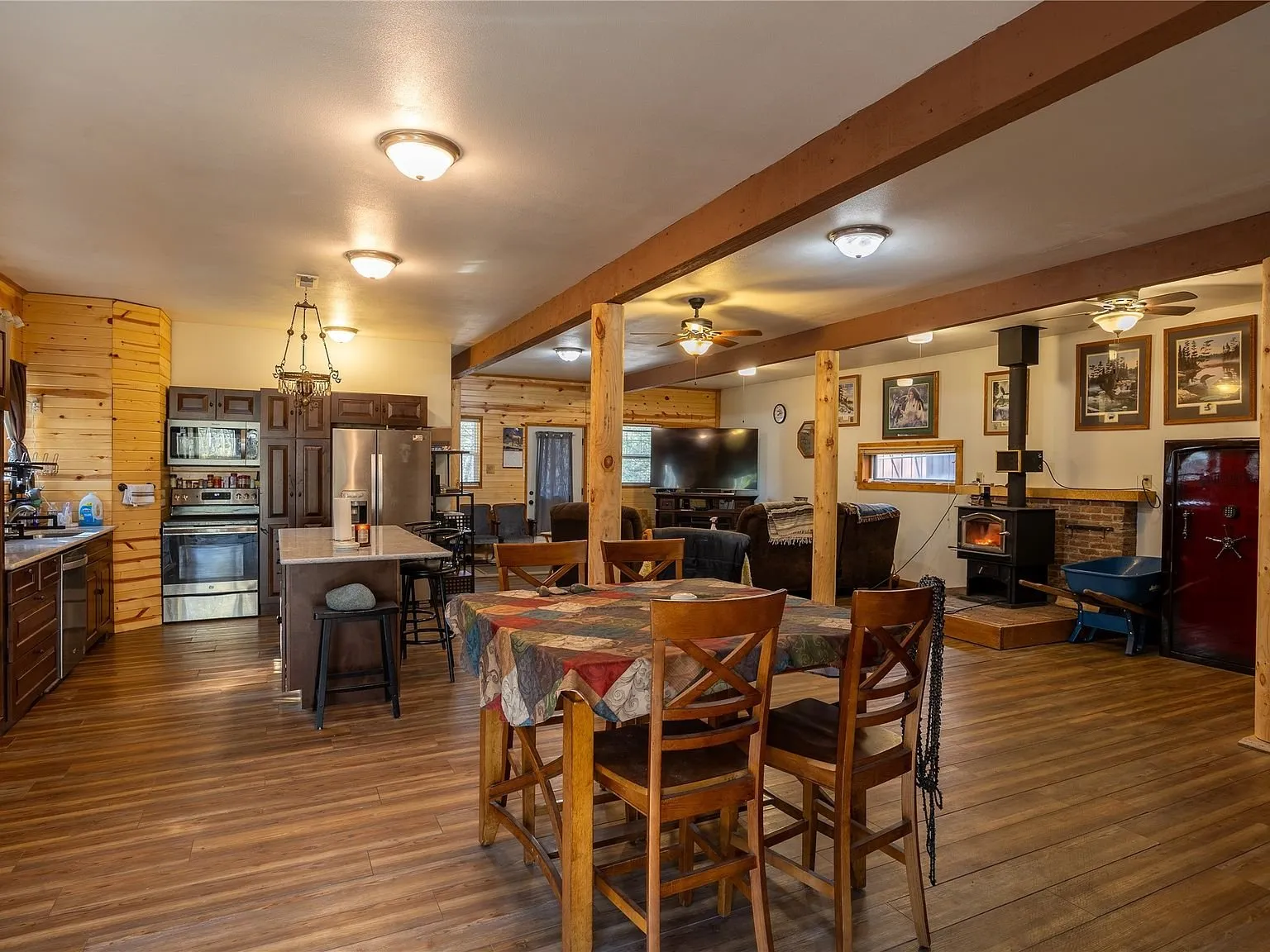 The open kitchen and dining area with wood floors and a wood-burning stove in the background