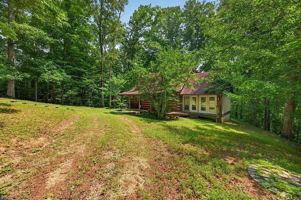 The log home and detached structure seen from across the mowed yard