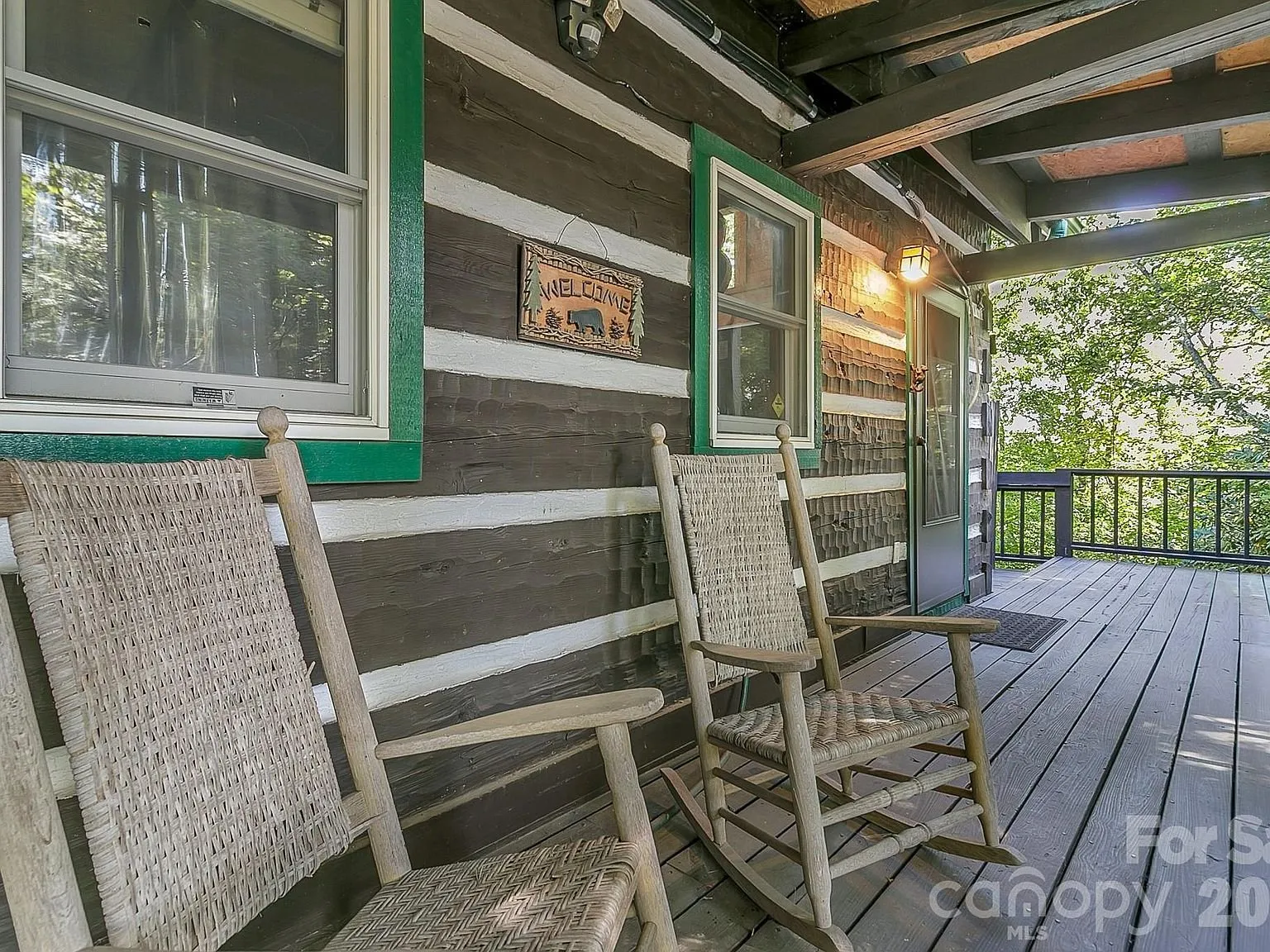 A covered porch with woven rocking chairs overlooking the trees