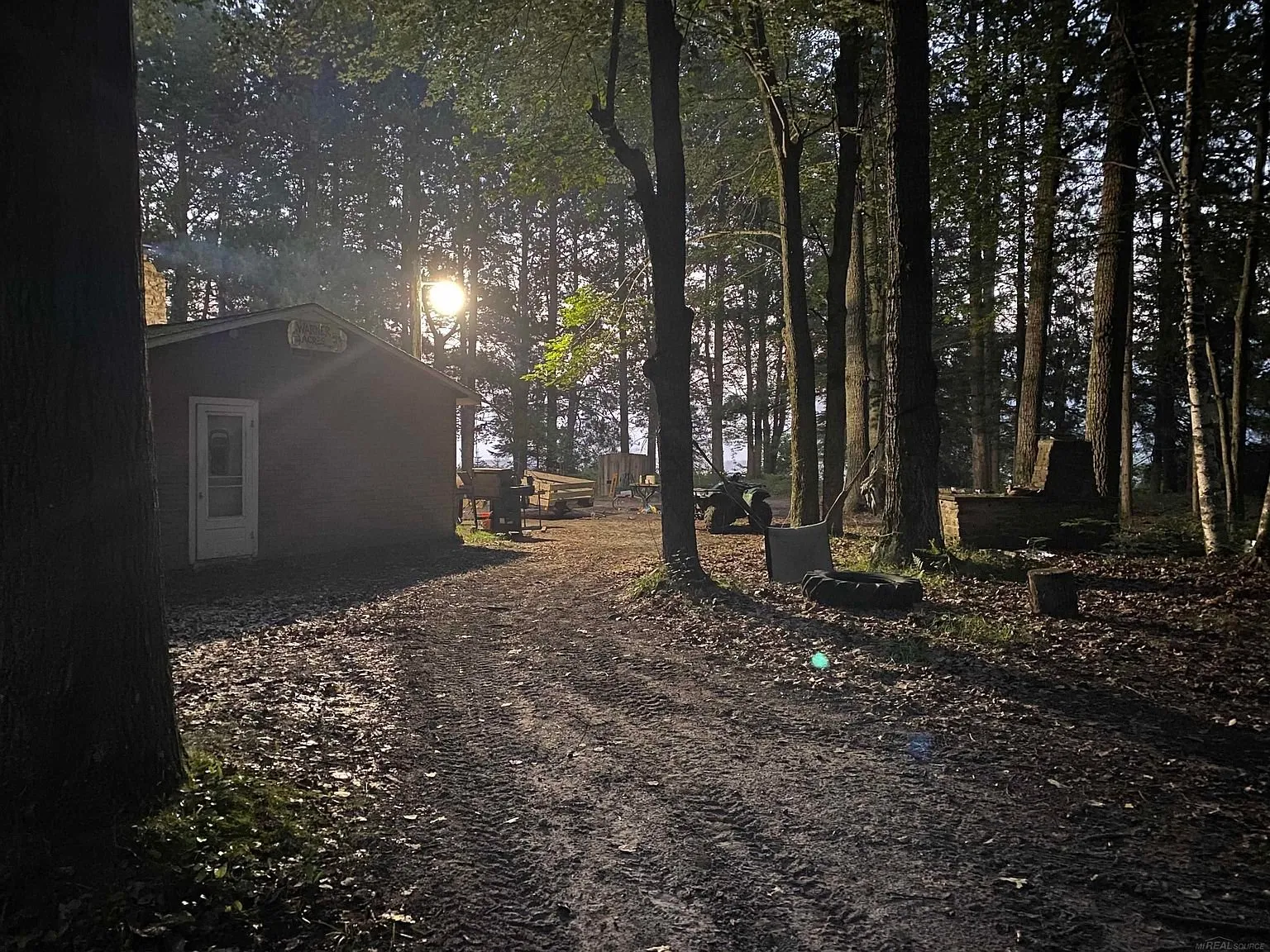 The cabin and the yard at dusk with the water through the trees
