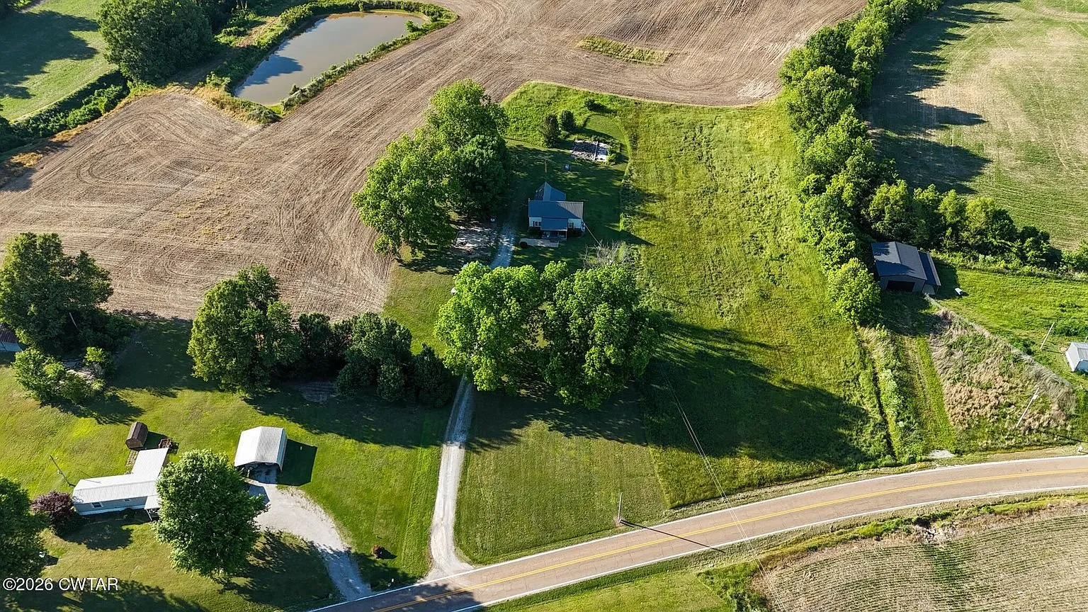 Aerial of the house and its trees between the road and the crop fields