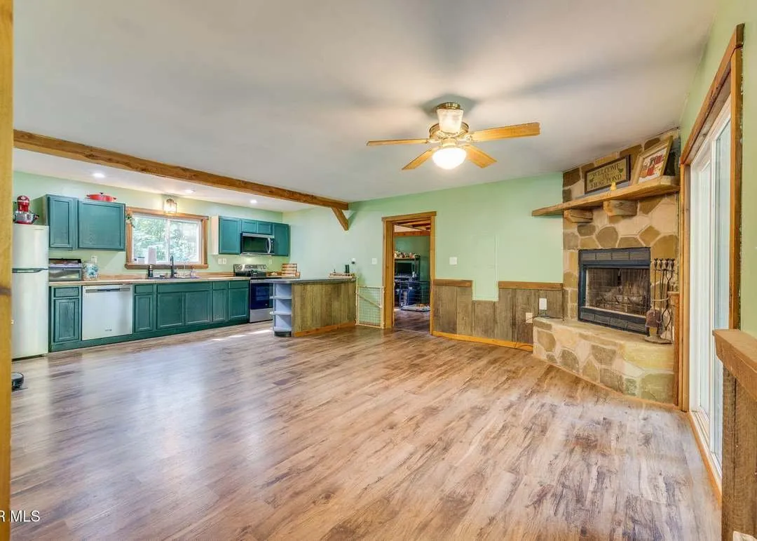The open living area with a stone fireplace and wood flooring