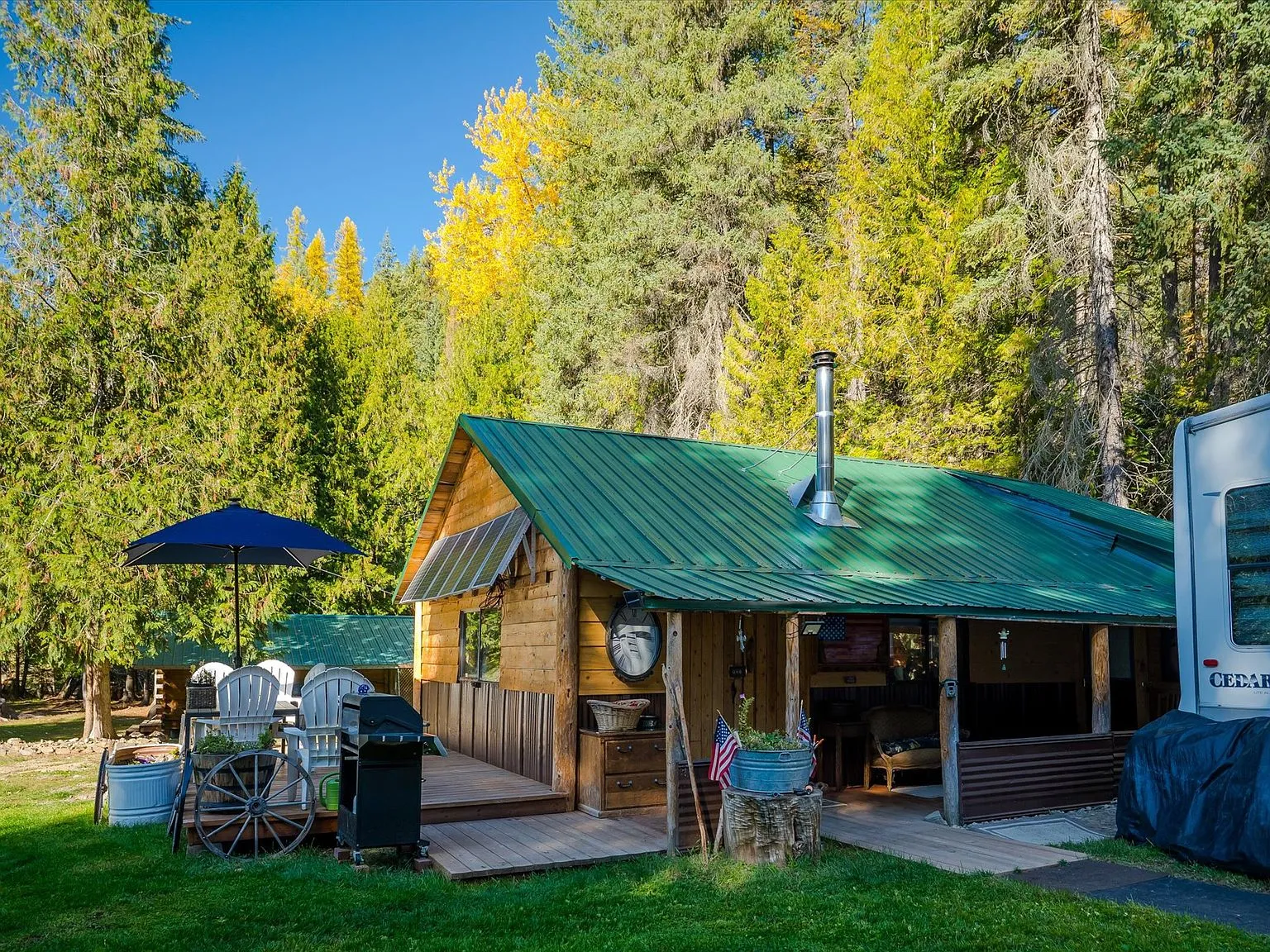 The cabin and covered porch seen from the lawn, with an umbrella table and wagon-wheel accents