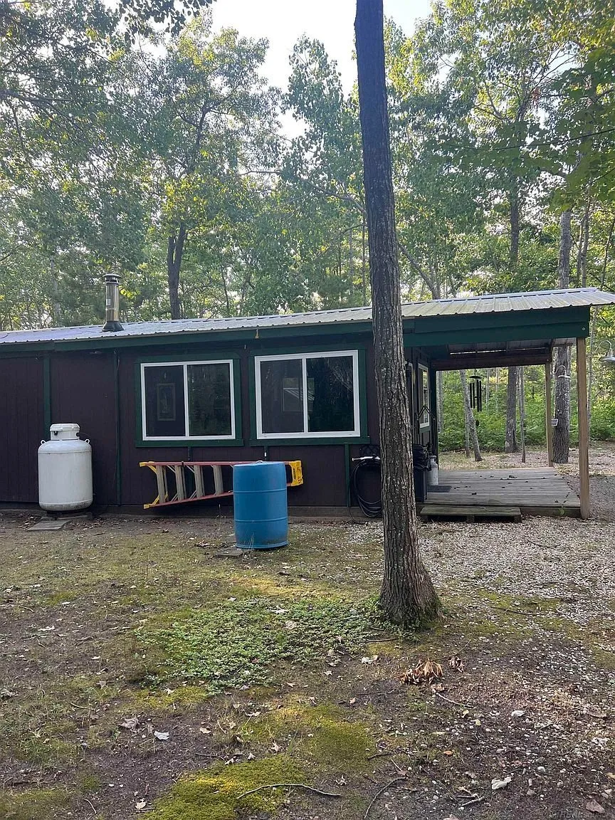 The side of the cabin with the propane tank, the barrel and the porch