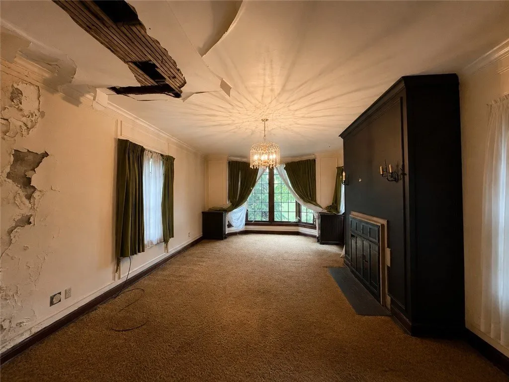 The dining room with the chandelier, the fireplace and peeling plaster on the ceiling