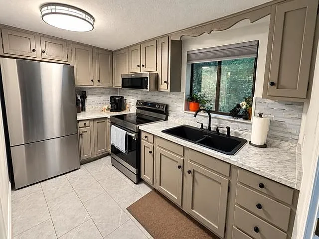 The full bathroom with a dark vanity, patterned shower curtain and wood-look flooring