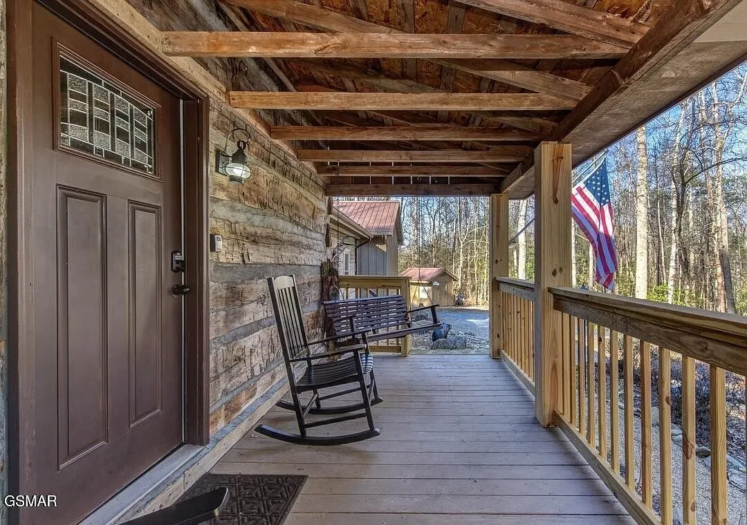 The covered front porch with rocking chairs and the flag at the rail