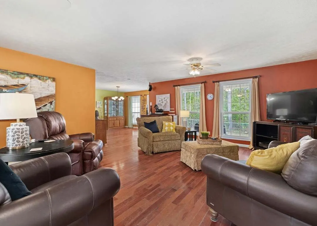 The living room with leather seating and hardwood floors opening to the dining area