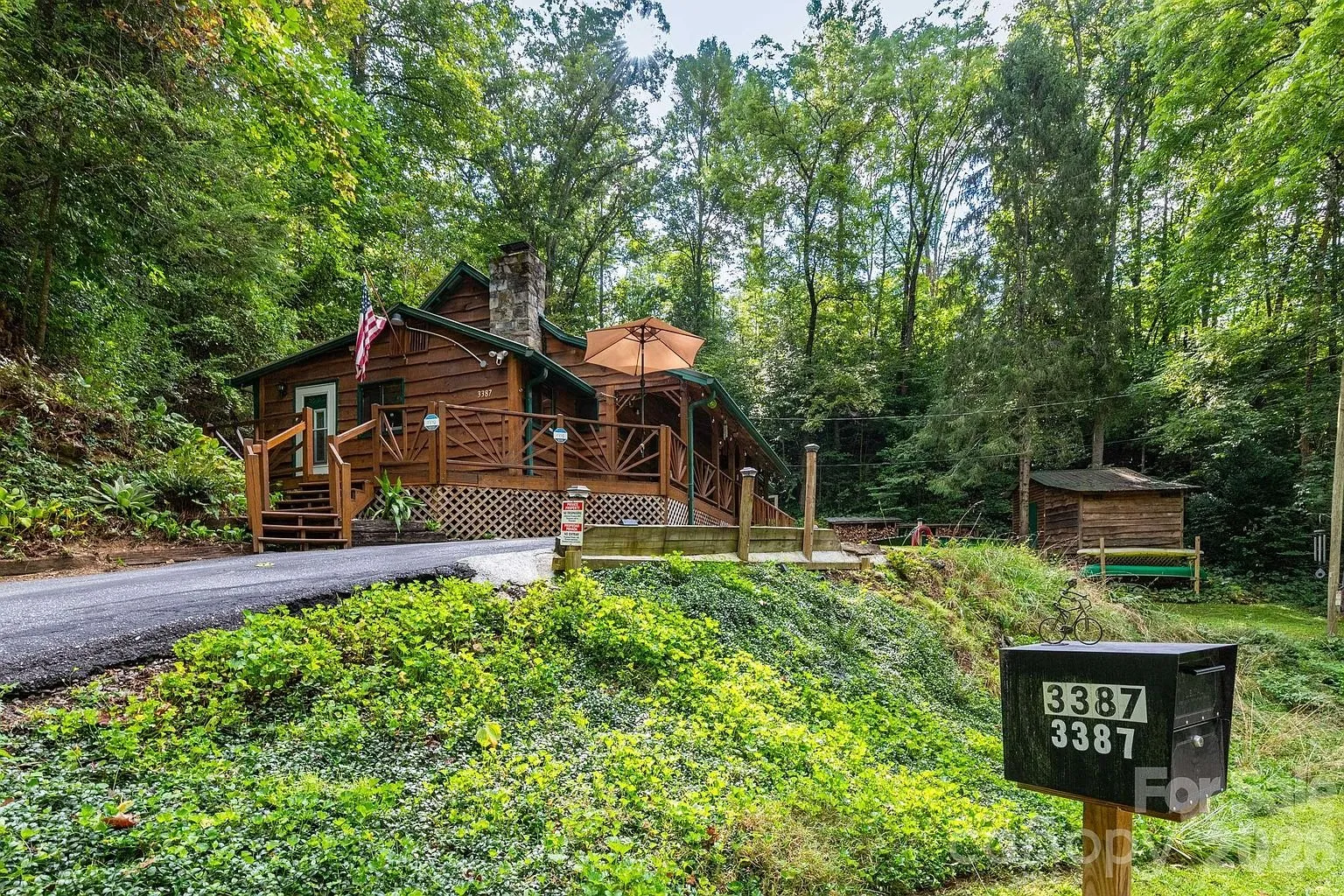 The cottage above the paved drive with the mailbox at the road