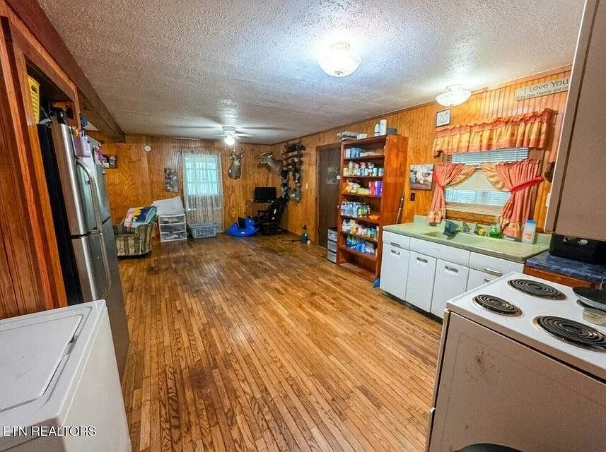 A second kitchen view with a stocked pantry shelf, curtained window and range