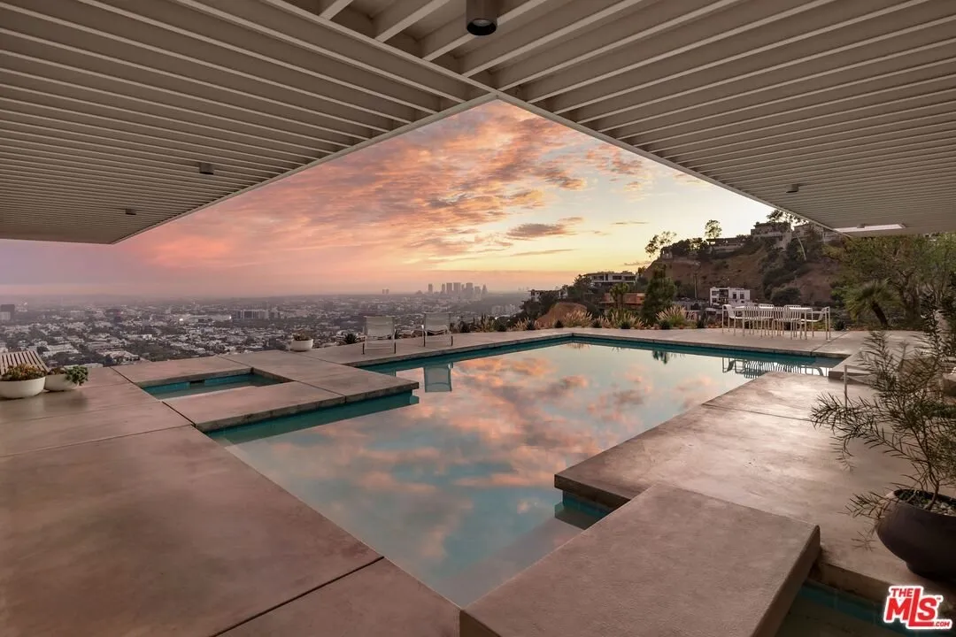 The pool at sunset reflecting pink cloud, the terrace running to the drop