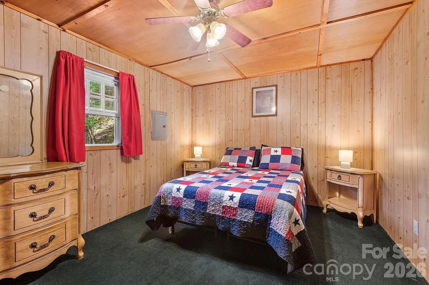 A bedroom with the quilted bed, the dresser and the red curtains