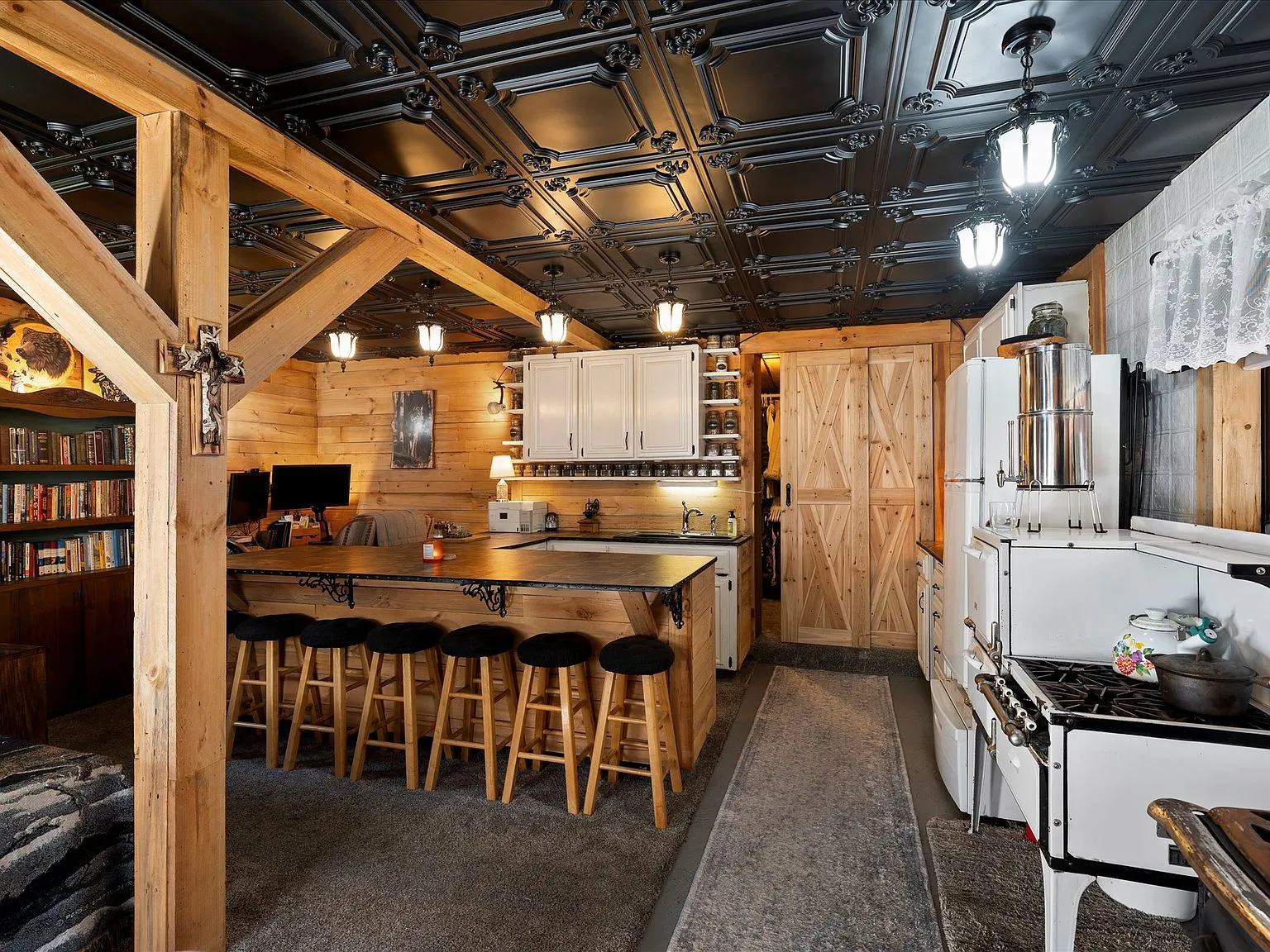 The open-plan kitchen and living area under a pressed-tin ceiling, with a barstool counter
