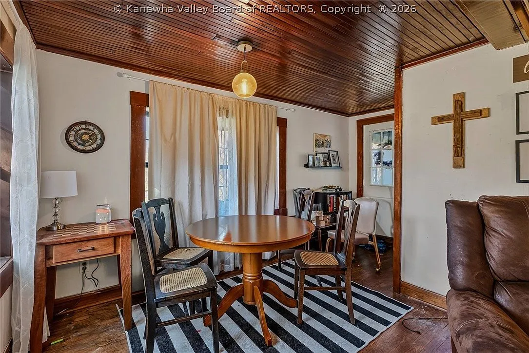 The galley kitchen with white cabinets, dark countertops and a garden window