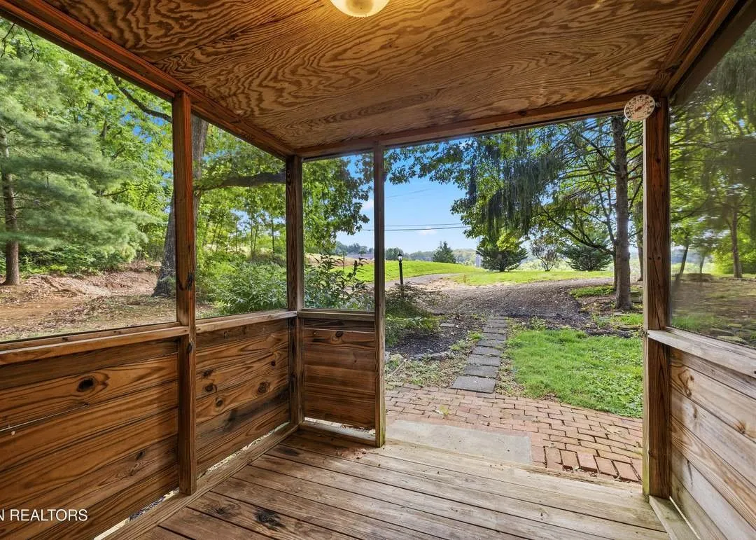 The screened porch overlooking the open field beyond the house