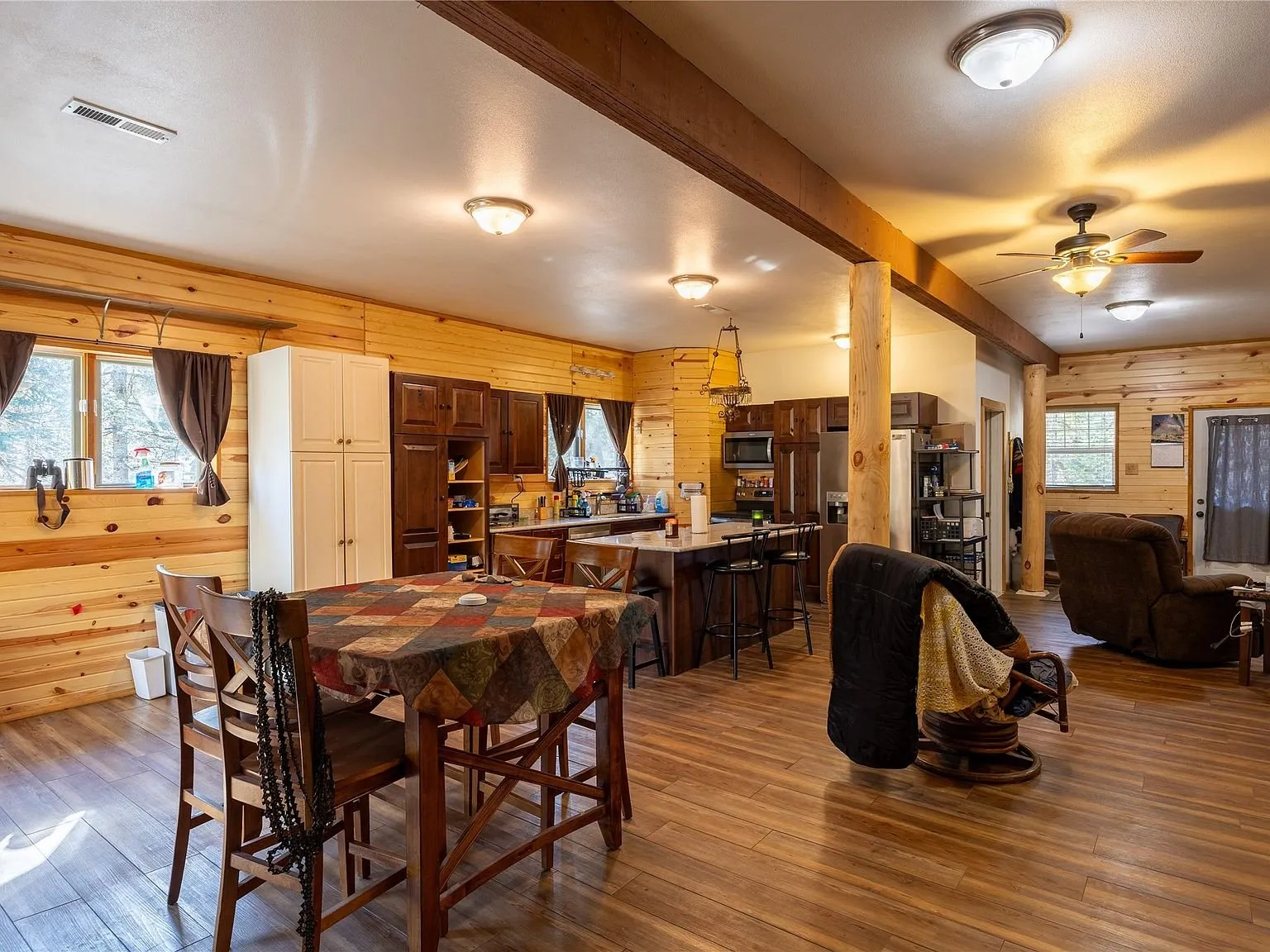 The dining table and seating area under knotty pine walls