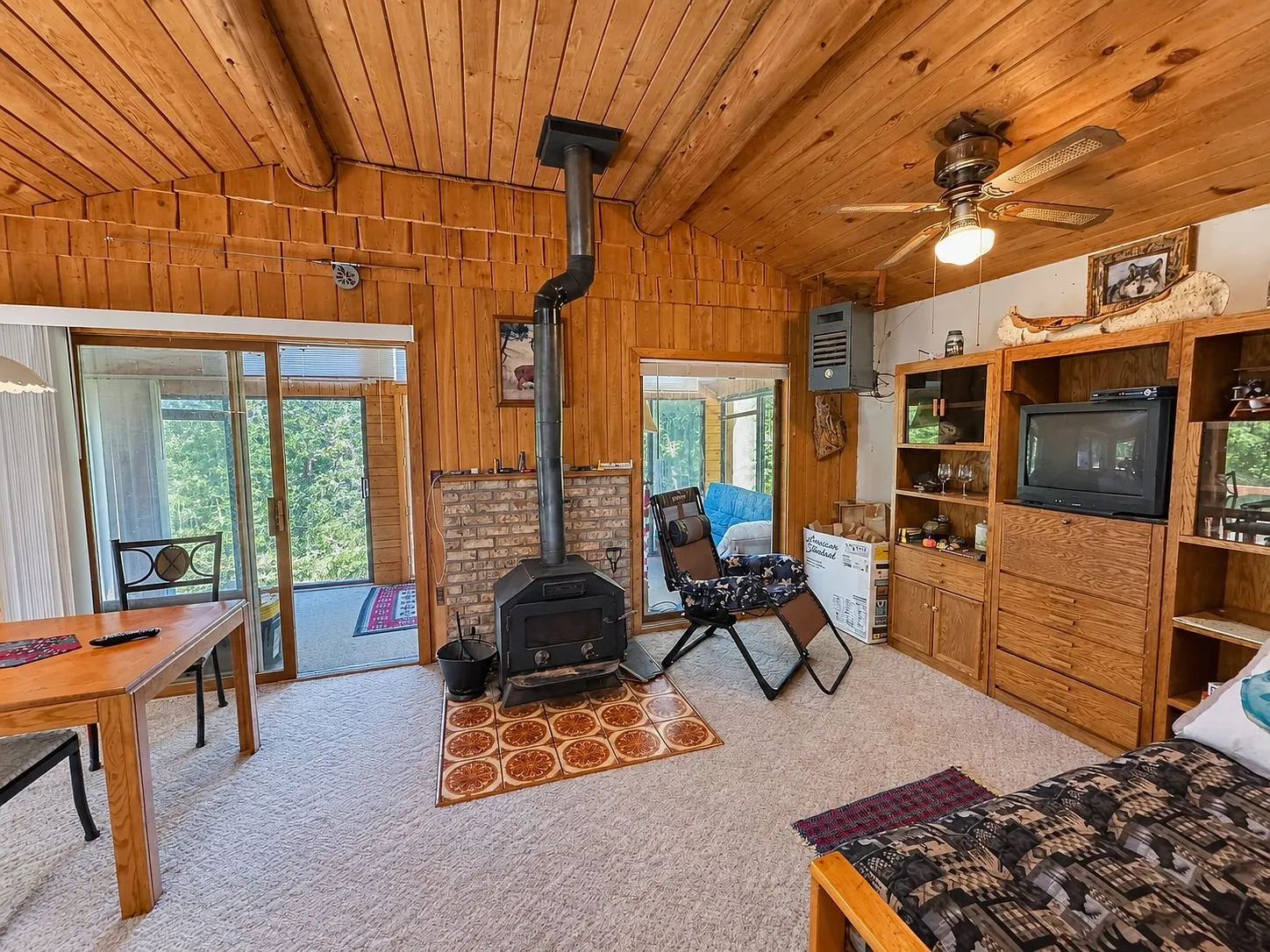 The living room with the wood stove on its brick hearth and the ceiling fan