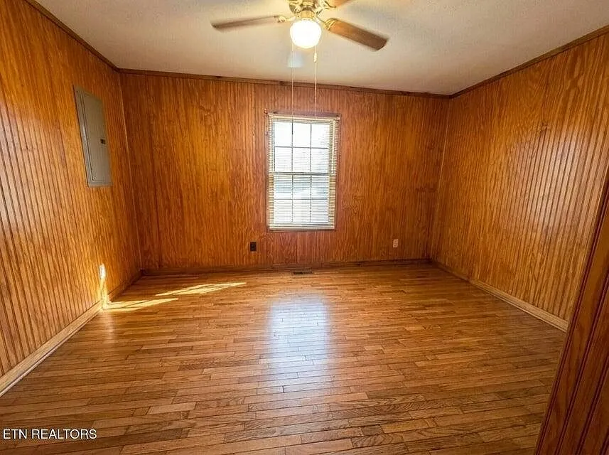 The main-level primary bedroom with wood paneling and a window