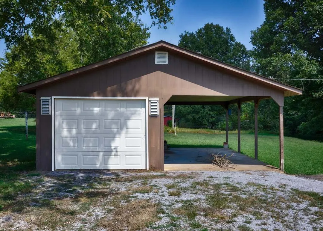 The detached garage and open carport structure near the driveway