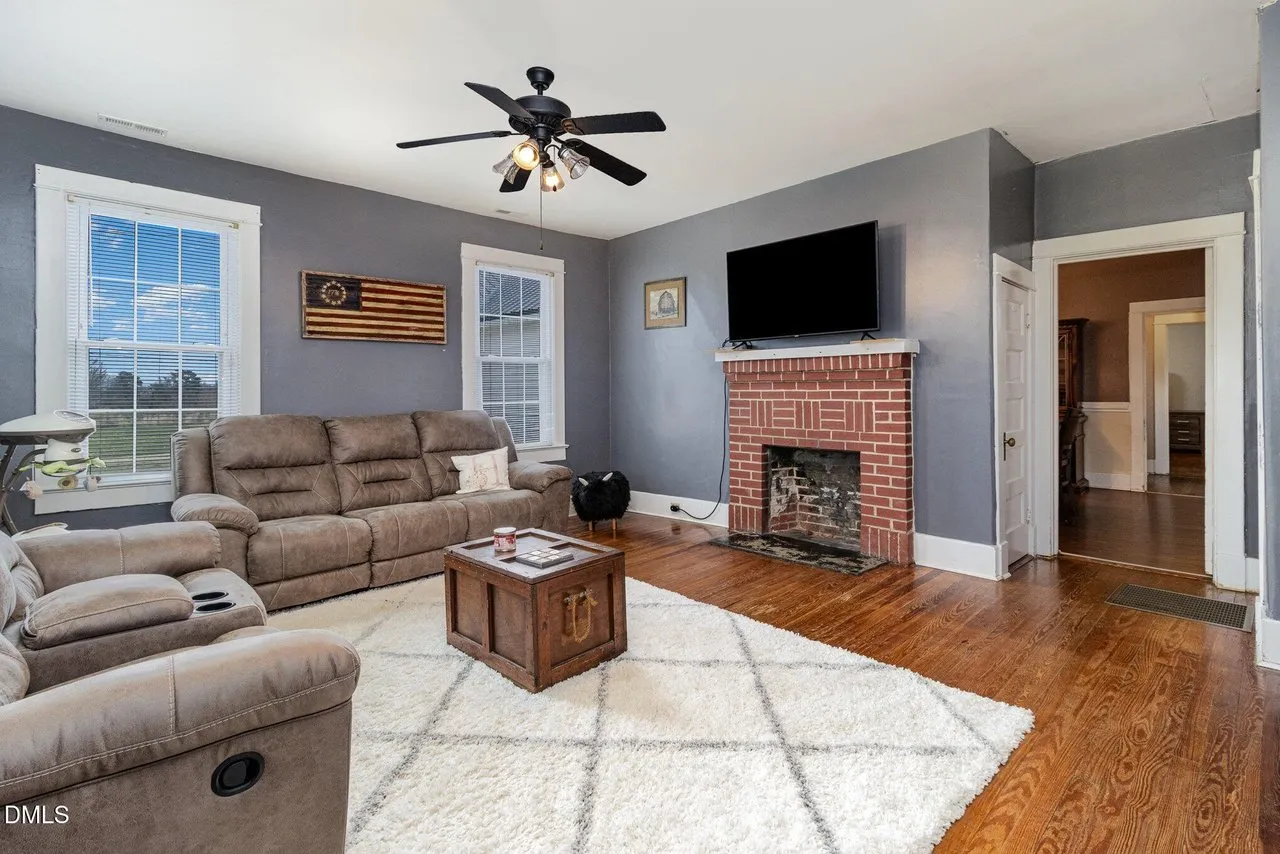 Living room with a fireplace, recliners, a ceiling fan and wood floors