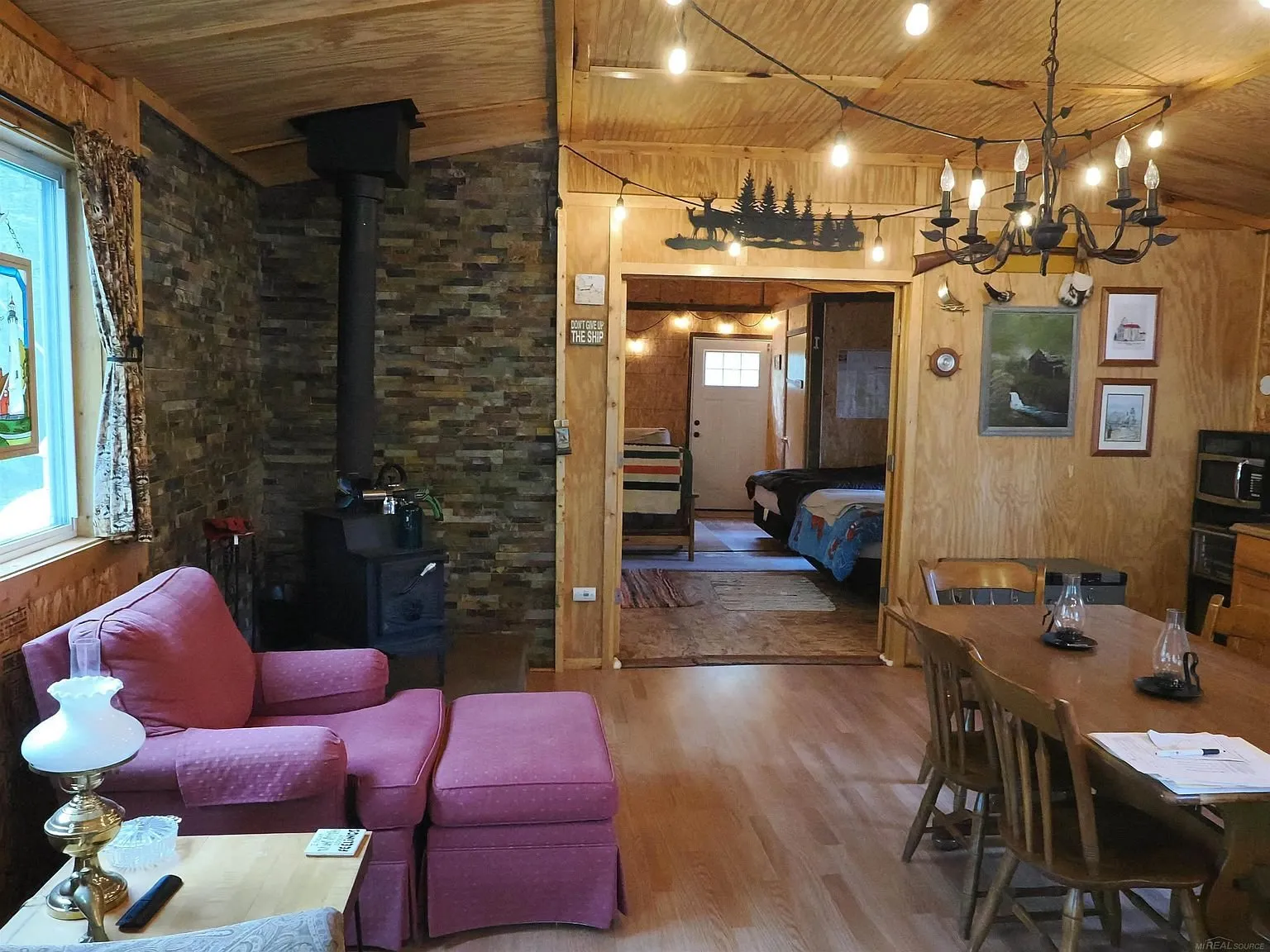 The common room with the wood stove on its stone wall, the red chairs and the table
