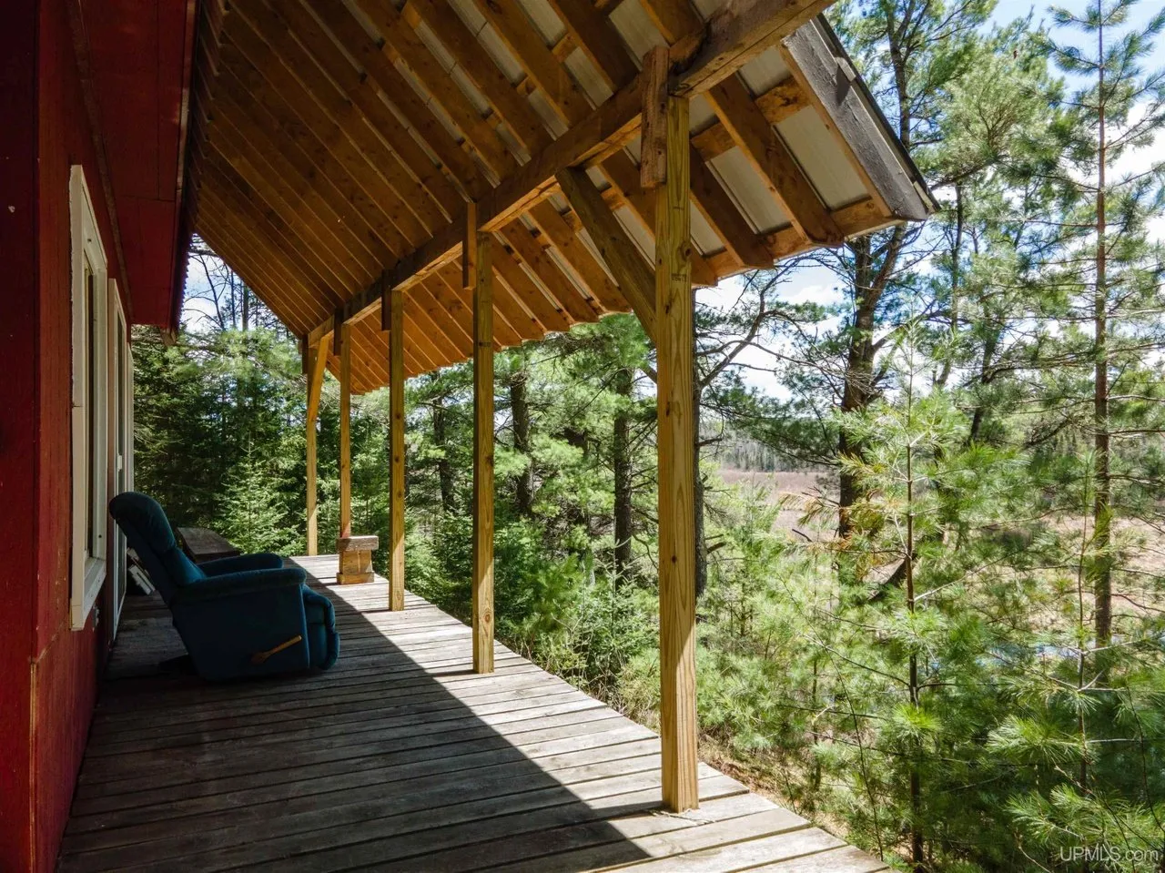 Along the covered porch with a chair looking out through the trees